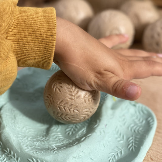 Hand holding a textured ball on a light blue surface with a blurred background