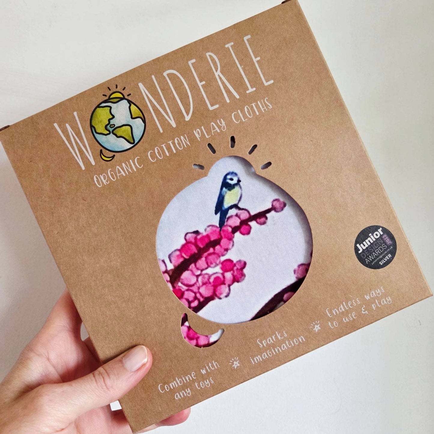 Wonderie organic cotton play cloth packaging held by a hand on a white background