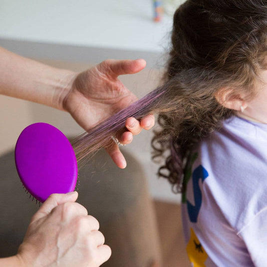 Person brushing a child's hair with Pink Hair Mascara in it