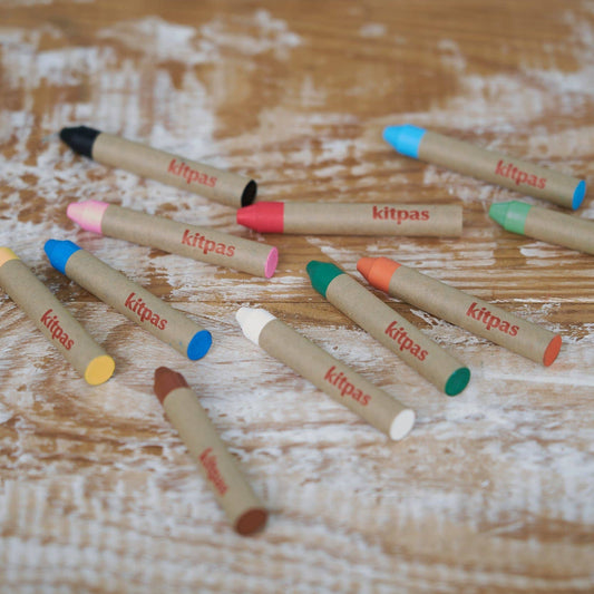 Colorful lip pencils with 'Kitpas' branding on a wooden surface