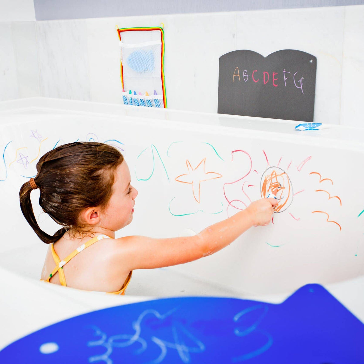 Child drawing on a bath with colorful bath crayons