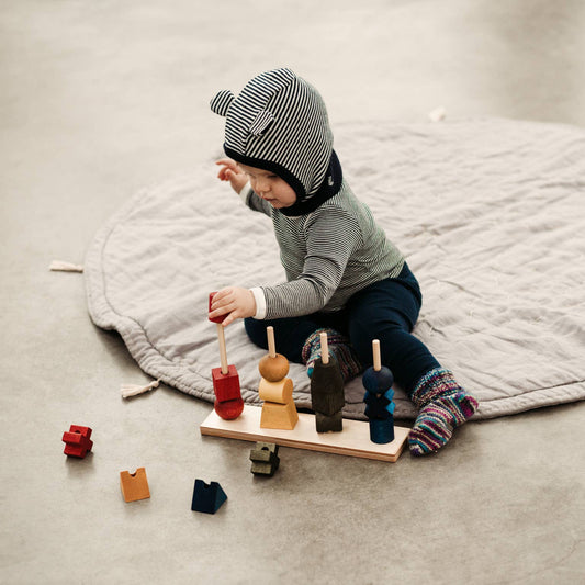 Child playing with wooden toys on a large mat