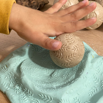 Hand interacting with a textured green surface and stone-like object on a wooden background