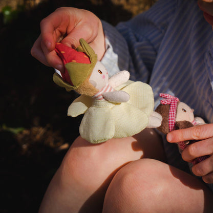 Child holding a plush toy and a small object outdoors