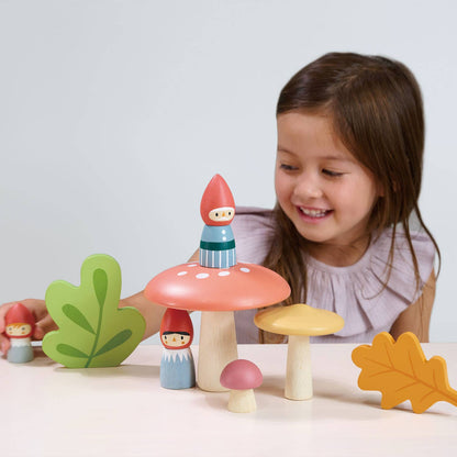 Child playing with colorful wooden mushrooms and gnomes on a white background
