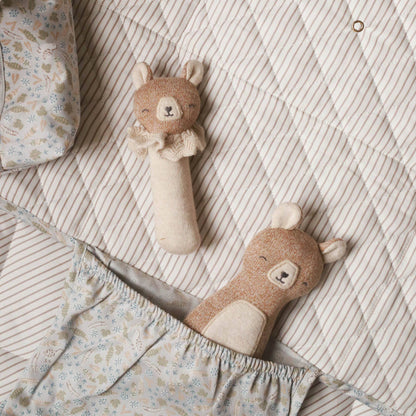 Two plush baby organic rattle toys shaped like bears, nestled in a striped and floral baby blanket.