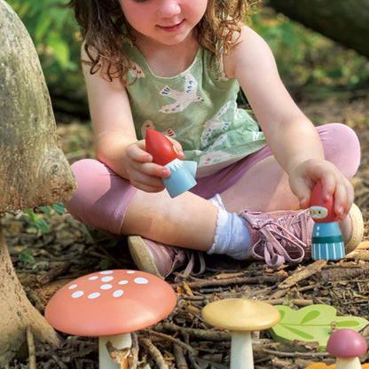 Child playing with toy mushrooms in a forest setting