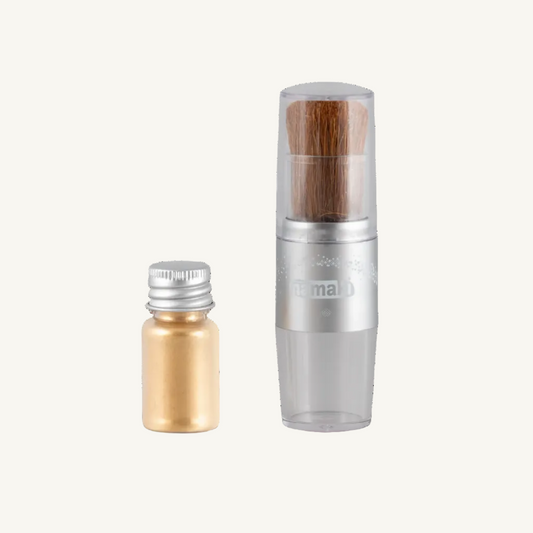 Namaki makeup brush and a small gold glitter bottle on a white background.