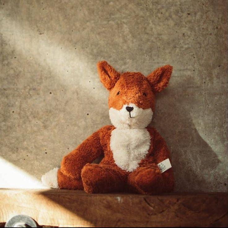 Stuffed fox toy on a textured surface with a warm glow