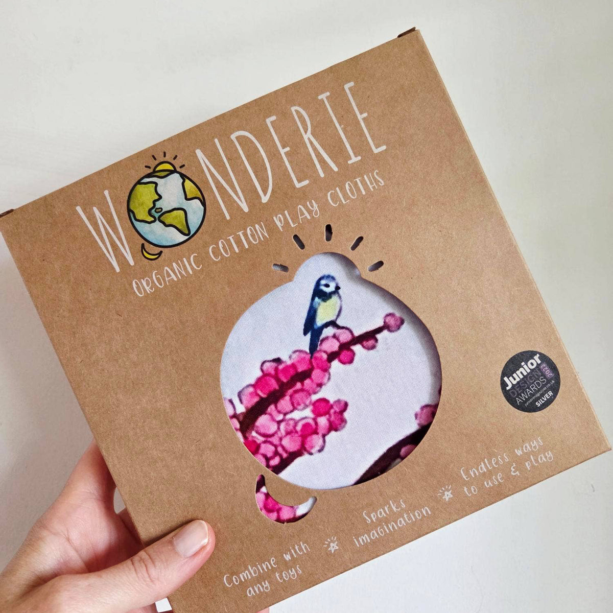 Wonderie organic cotton play cloth packaging held by a hand on a white background