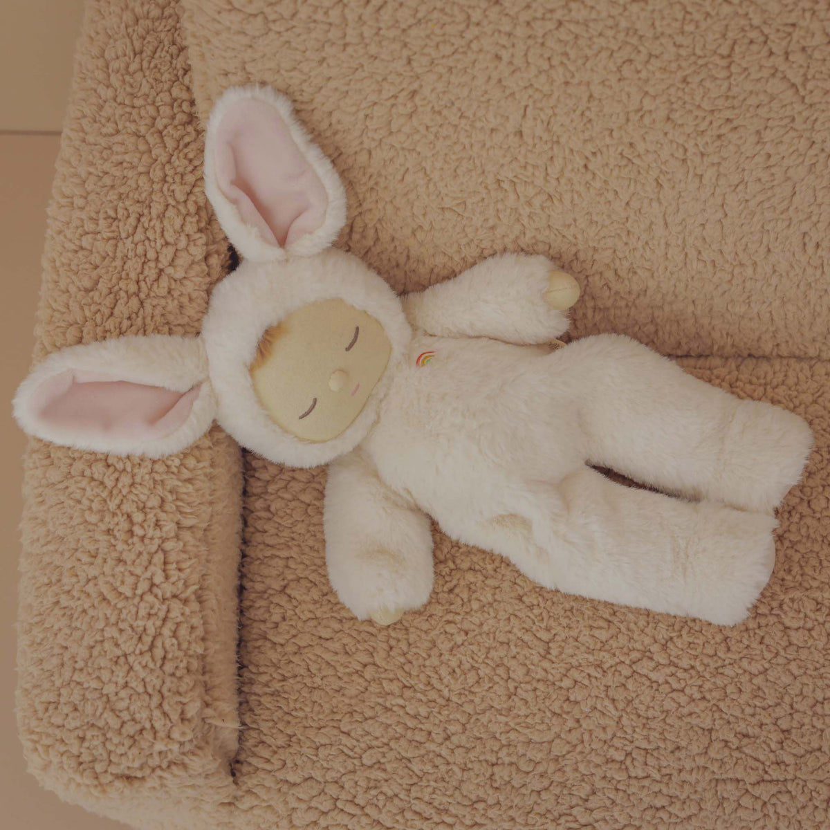 White plush bunny toy on a beige textured surface
