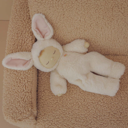 White plush bunny toy on a beige textured surface