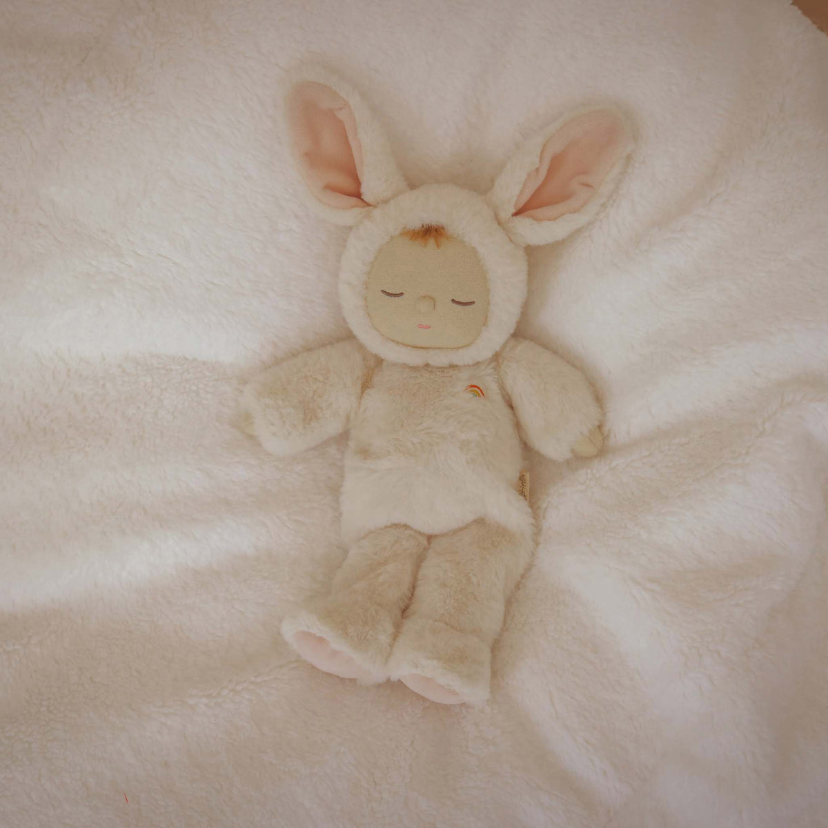 Plush toy in a bunny costume lying on a soft, light-colored surface