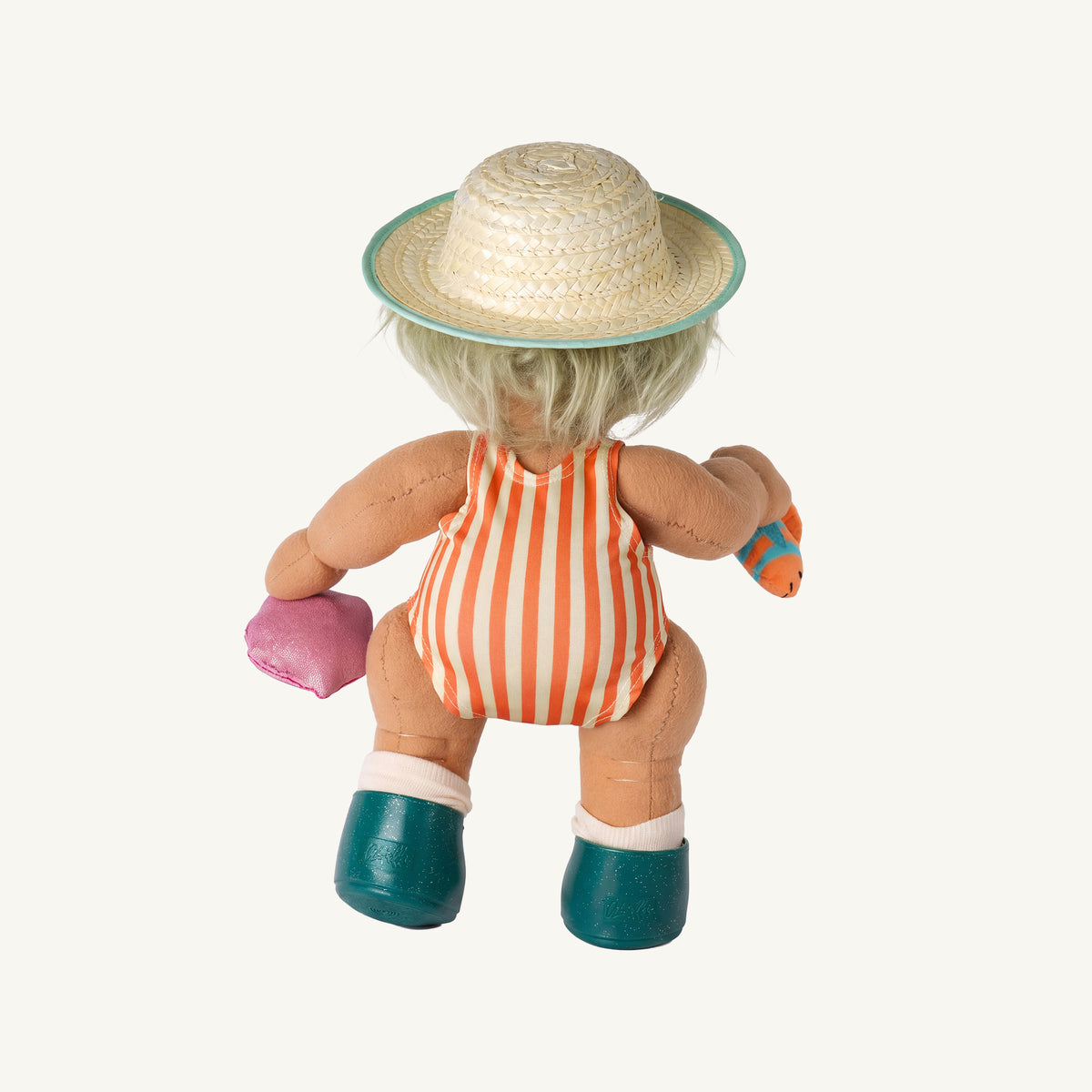 A dinkum doll viewed from behind wearing a straw hat with a teal brim, an orange and white striped swimsuit, teal shoes, and holding a pink heart and a small orange fish.
