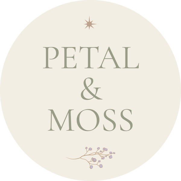 A circular beige logo or label with the words 'PETAL & MOSS' in muted green-gray lettering, a small starburst above, and a delicate floral branch with pale purple blossoms below.