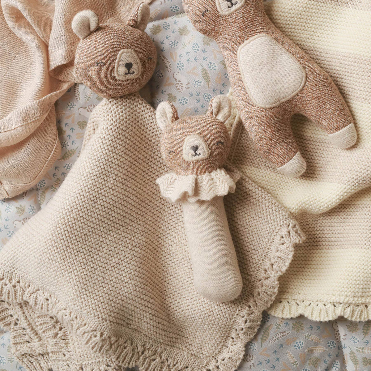 Three knitted organic bear toys on a textured surface.