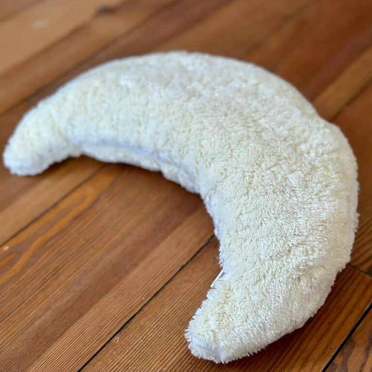 White crescent-shaped pillow on a wooden floor