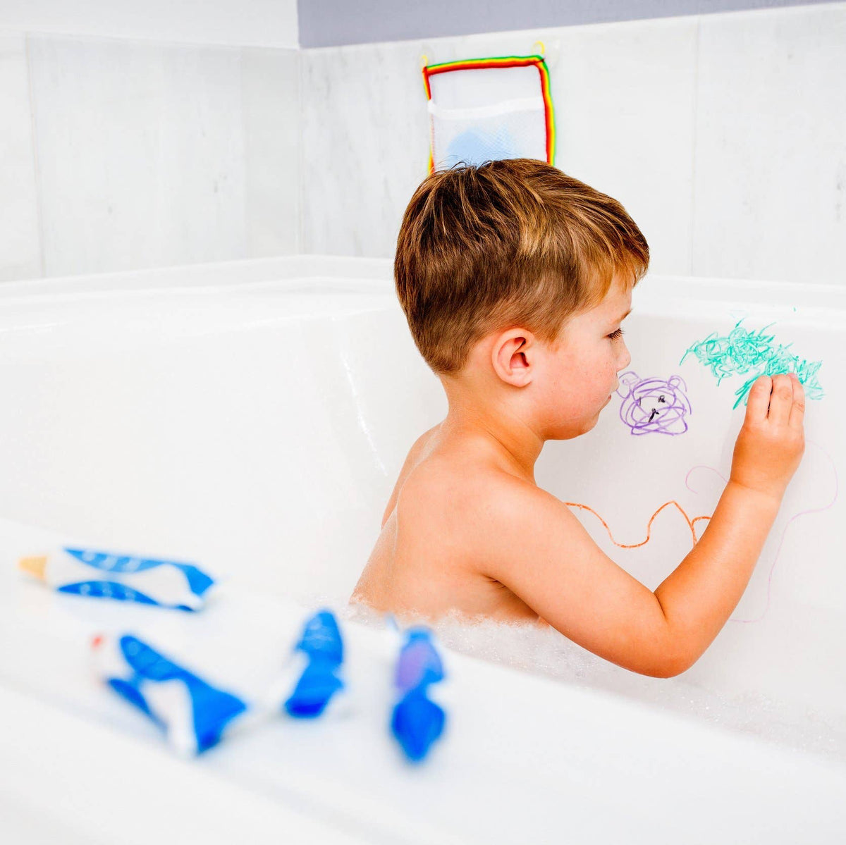 Child drawing on a white bath with colorful bath crayons