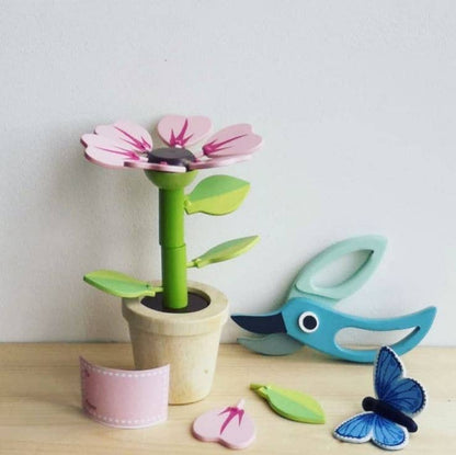 Colorful toy flower with a watering can and butterfly on a wooden surface