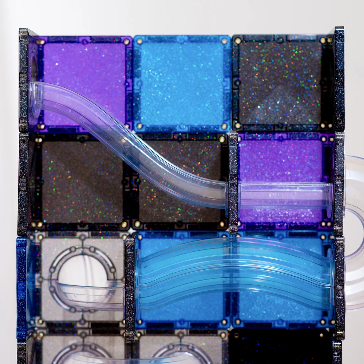 Multiple glittery CONNETIX tiles in purple, blue, black, and clear, connected by curved transparent tubes.