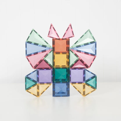 A colorful magnetic tile structure built into a butterfly-like shape, made from translucent square and triangular pieces in pink, blue, green, yellow, and purple, photographed on a clean white background.
