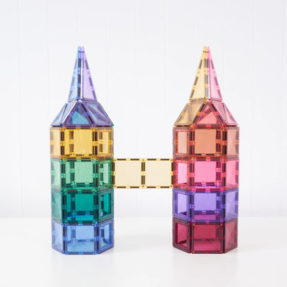 Two colorful magnetic building towers connected by a bridge, made from translucent square tiles in blue, green, purple, yellow, orange, and pink, set against a white background.