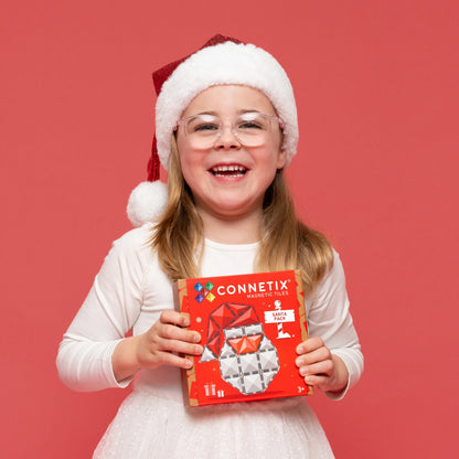 Girl holding a CONNETIX Magnetic tiles Christmas Santa Pack against a red background